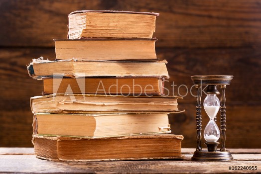 Picture of stack of old books and retro hourglass